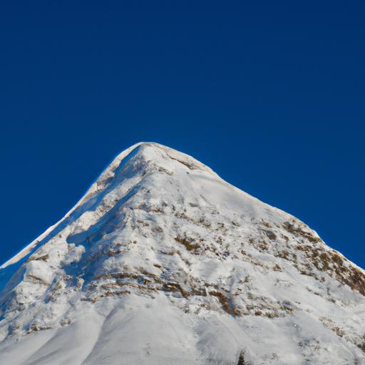 Một đỉnh núi phủ chan chứa tuyết với khung trời xanh xao nhập trong cả hâu phương.